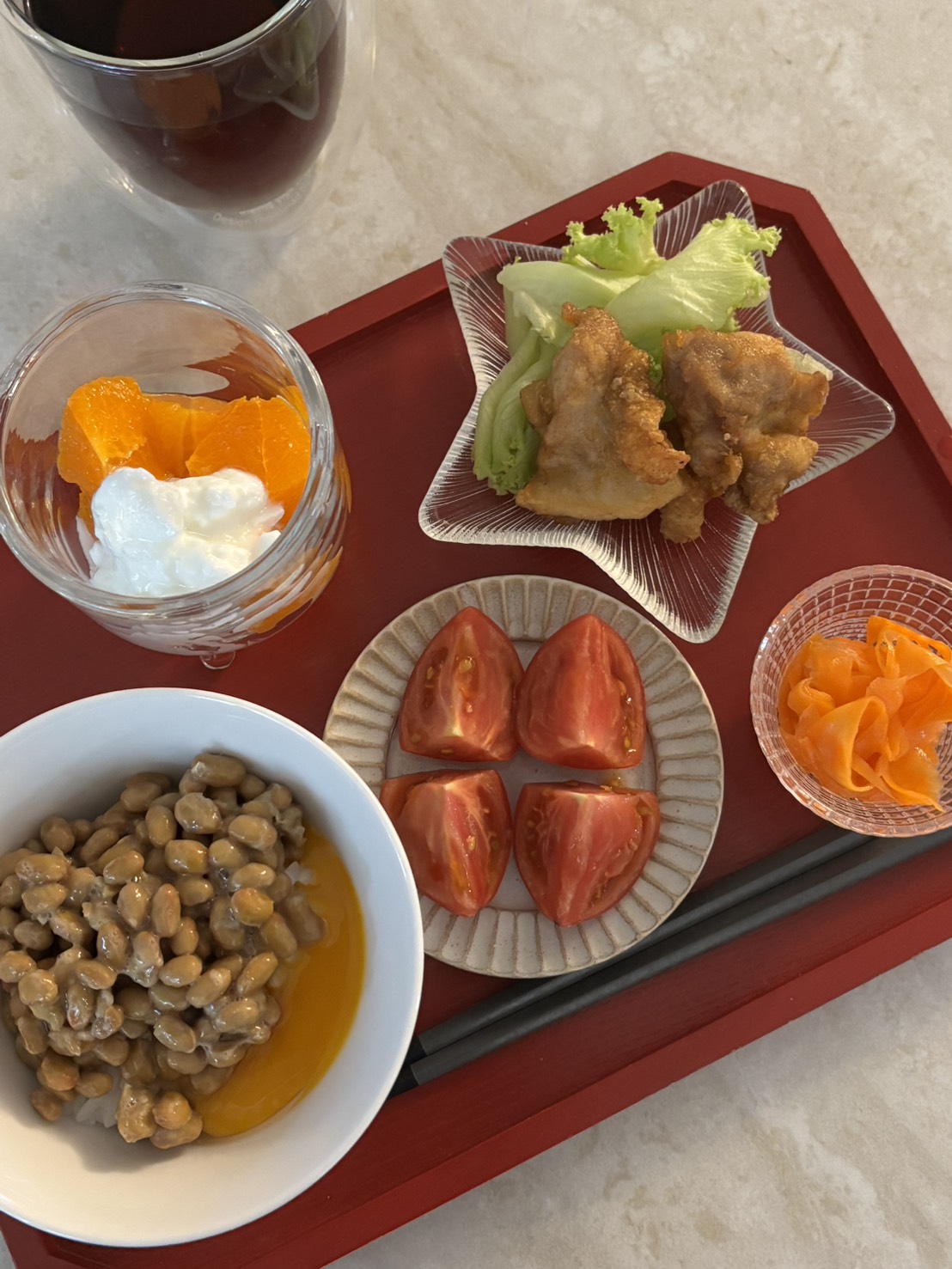 女将のとある朝ごはん。納豆ごはんと、小皿に盛り付けたおかずやフルーツ
