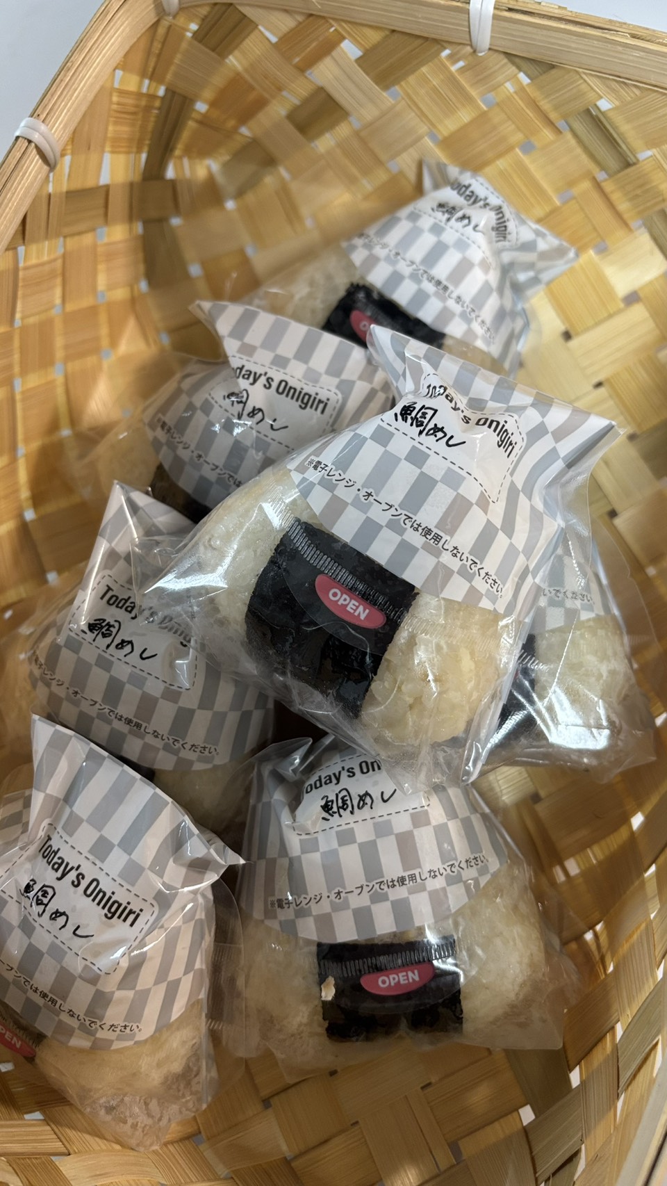 おにぎりフィルムに包み「鯛めし」と手書きした鯛めしおにぎりを、かごに盛ったところ